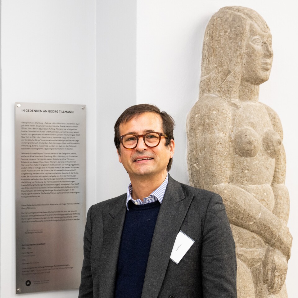 Hugo Tillman, Urenkel von Georg Tillmann vor der Gedenktafel neben einer der beiden Kaminfiguren von Gustav Heinrich Wolff (1986–1934) im Hubertus-Wald-Forum der Hamburger Kunsthalle © Hamburger Kunsthalle, Foto: Romanus Fuhrmann Hugo Tillman, Urenkel von Georg Tillmann vor der Gedenktafel neben einer der beiden Kaminfiguren von Gustav Heinrich Wolff (1986–1934) im Hubertus-Wald-Forum der Hamburger Kunsthalle © Hamburger Kunsthalle, Foto: Romanus Fuhrmann